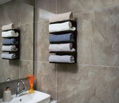 towels are hanging on the wall above a sink in a bathroom with marble walls and tile flooring