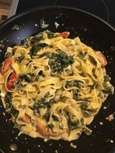 pasta with spinach and tomatoes in a skillet