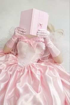 a woman in a pink dress is holding a book