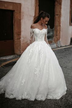 a woman in a white wedding dress is walking down the street with her hand on her hip