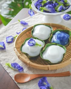 some blue and white flowers are in a basket on a table with spoons next to it