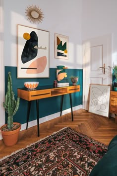 a living room with green walls and wooden floors, artwork on the wall above a table