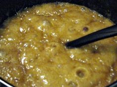 a pan filled with food cooking on top of a stove next to a spatula