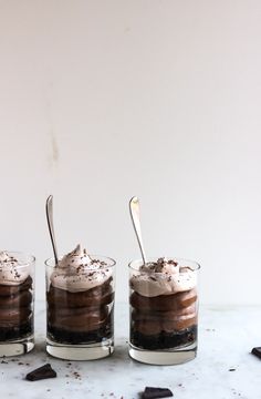 three glasses filled with desserts sitting on top of a table