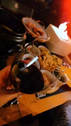 a person holding a wine glass with food in it