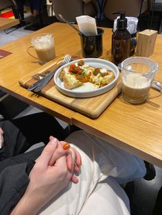 a person sitting at a table with food in front of them and drinks on the side