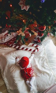 a baby laying on top of a blanket next to a christmas tree