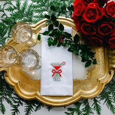 red roses and greenery sit on top of a gold tray with white napkins