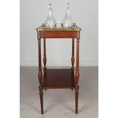 a small wooden table with two glass bottles on it's top and bottom shelf