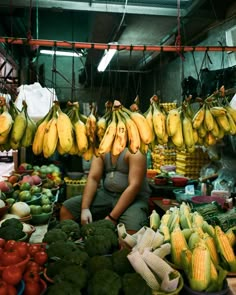 a woman sitting in front of a table filled with lots of fruits and vegetables