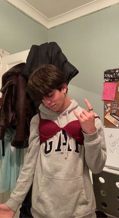 a young man wearing a red bow tie standing in front of a closet full of clothes