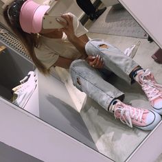 a woman taking a selfie in front of a mirror wearing pink sneakers and jeans