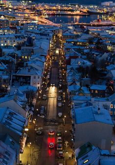 an aerial view of a city at night with snow on the ground and cars parked along the street