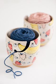 two bowls with yarn in them on a white surface, one is blue and the other is pink