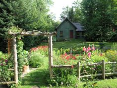 the garden is full of colorful flowers and greenery, with a green house in the background