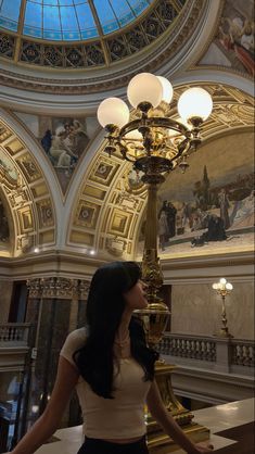 a woman standing next to a lamp in a building