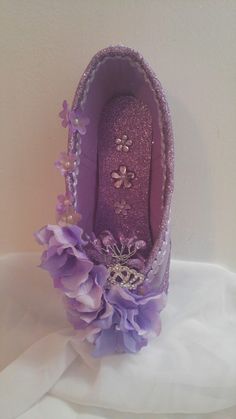 a purple shoe with flowers and pearls on the inside is sitting on a white sheet