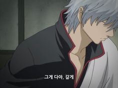 an anime character with grey hair and black shirt looking down at his left hand while standing in front of the camera