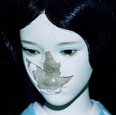 a close up of a doll's face with leaves on it