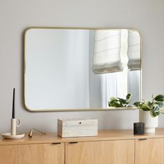 a wooden dresser with a large mirror on it's side and a plant next to it