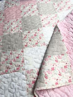 a pink and gray quilt on top of a bed