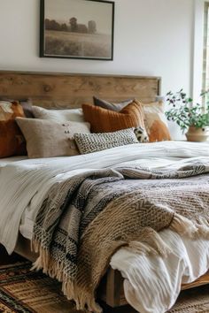 a bed with pillows and blankets on top of it in a bedroom next to a window