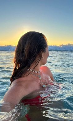 a woman is in the water at sunset