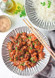 two plates filled with meat and rice next to some chopsticks on the side