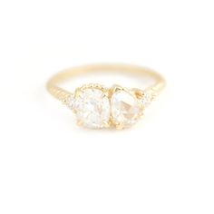 three stone ring in yellow gold with two diamonds on each side and an oval shaped diamond at the top