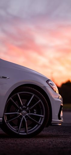 a white car parked in front of a sunset