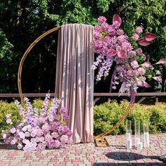 an outdoor ceremony setup with flowers and draping on the back drop cloth, surrounded by greenery