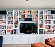 a living room filled with furniture and a flat screen tv sitting on top of a book shelf