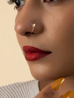 a close up of a woman with a nose ring and red lipstick on her lips