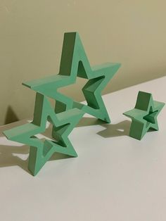 three green origami stars sitting on top of a white table next to each other