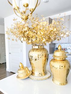 a vase with flowers in it sitting on top of a table next to two gold urns