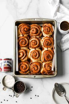 a baking pan filled with cinnamon rolls and coffee