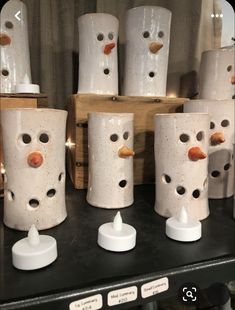 several white vases with holes in them sitting on a shelf next to each other