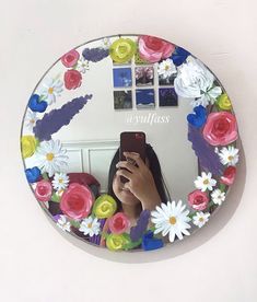 a woman taking a selfie in front of a mirror with flowers painted on it