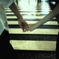 two people holding hands while crossing the street