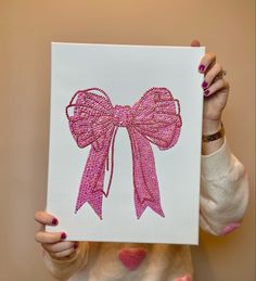 a woman holding up a card with a pink bow on it