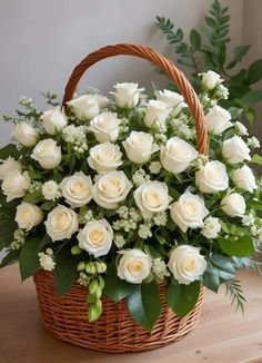 a basket filled with white roses on top of a wooden table