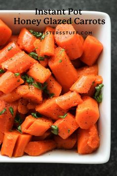 a white bowl filled with chopped carrots on top of a black countertop and garnished with parsley