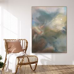 an abstract painting hangs on the wall next to a wicker chair and potted plant