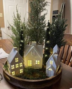 a wooden tray with small houses and trees in the center, on top of a table