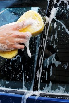 a person washing a car with a yellow sponge