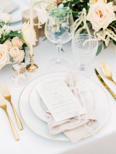 the table is set with white and gold place settings, silverware, and floral centerpieces