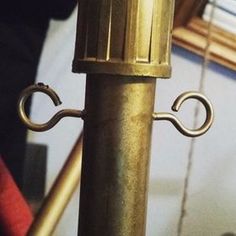 a close up of a metal pole with a light on it's end and a clock in the background