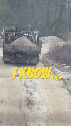 a dump truck driving down a dirt road