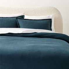 a bed with blue sheets and white pillows