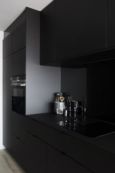 a kitchen with black cabinetry and counter tops in the middle of an empty room